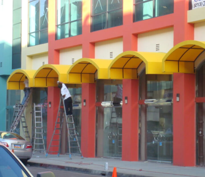 Yellow arched canvas awnings during installation, Los Angeles