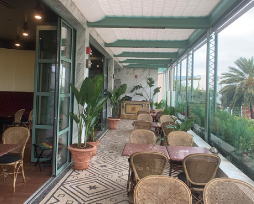 Clear outdoor curtains enclosing a long commercial patio under a trellis