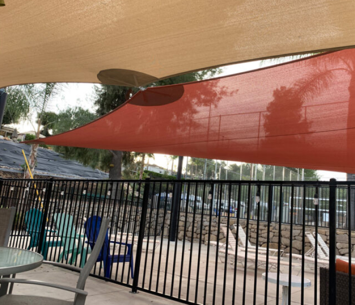Red and tan shade sails above a fenced patio, Riverside County