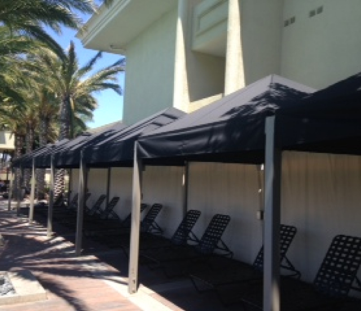 Row of black fabric cabanas beside a pool deck, Ventura County
