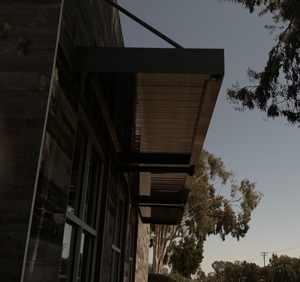 Black metal walkway canopy beside a building, Orange County