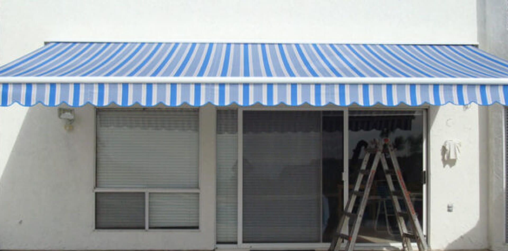 Blue-and-white striped retractable awning above a window, Orange County
