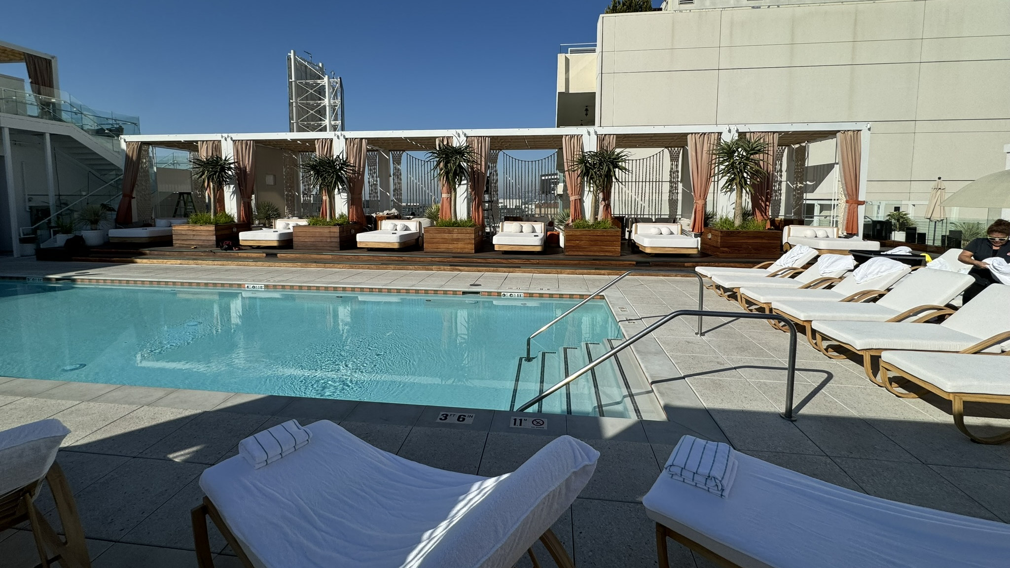 Row of white poolside cabanas with coral curtains on the rooftop pool deck of a boutique hotel in Hollywood