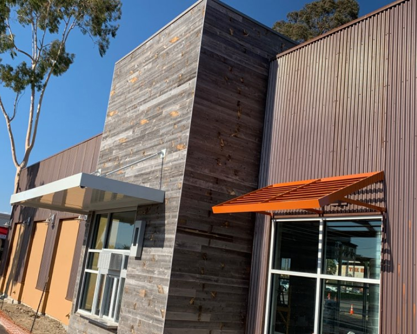 Multiple metal entrance and window canopies installed on a modern commercial building