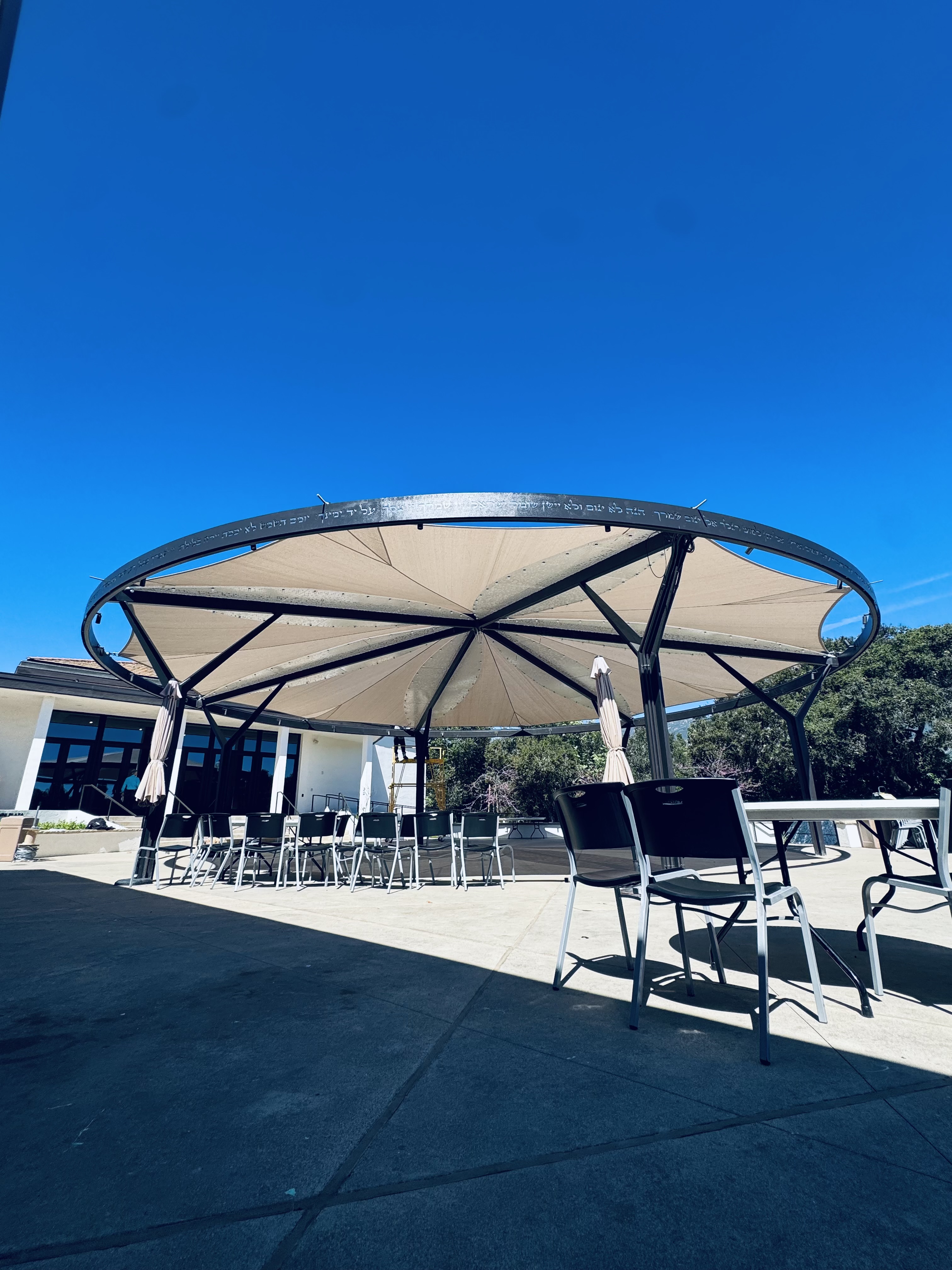 Round custom fabric canopy covering an outdoor gathering area at a B'NAI campus