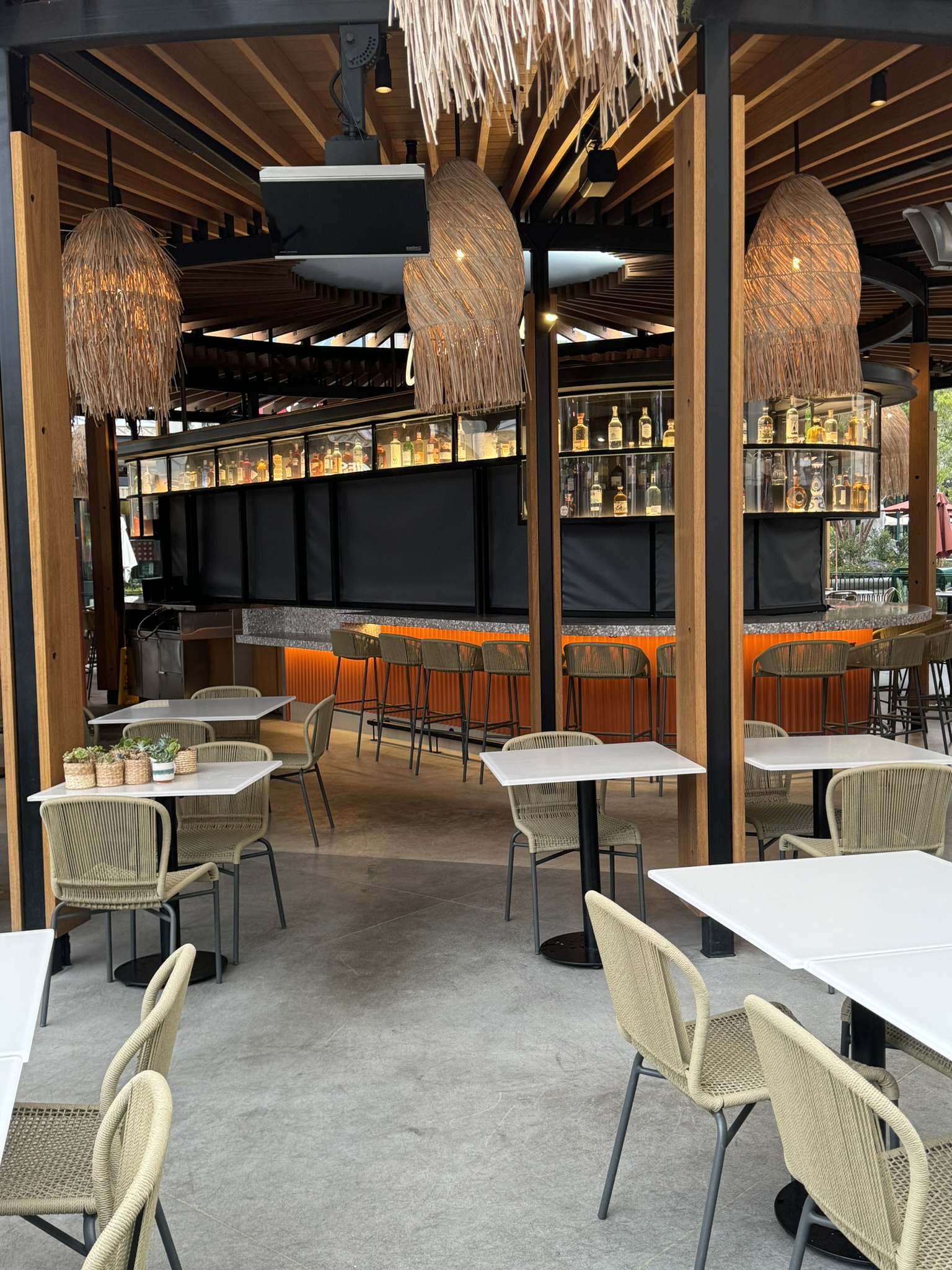 Wood pergola-style patio cover above an outdoor dining and bar area
