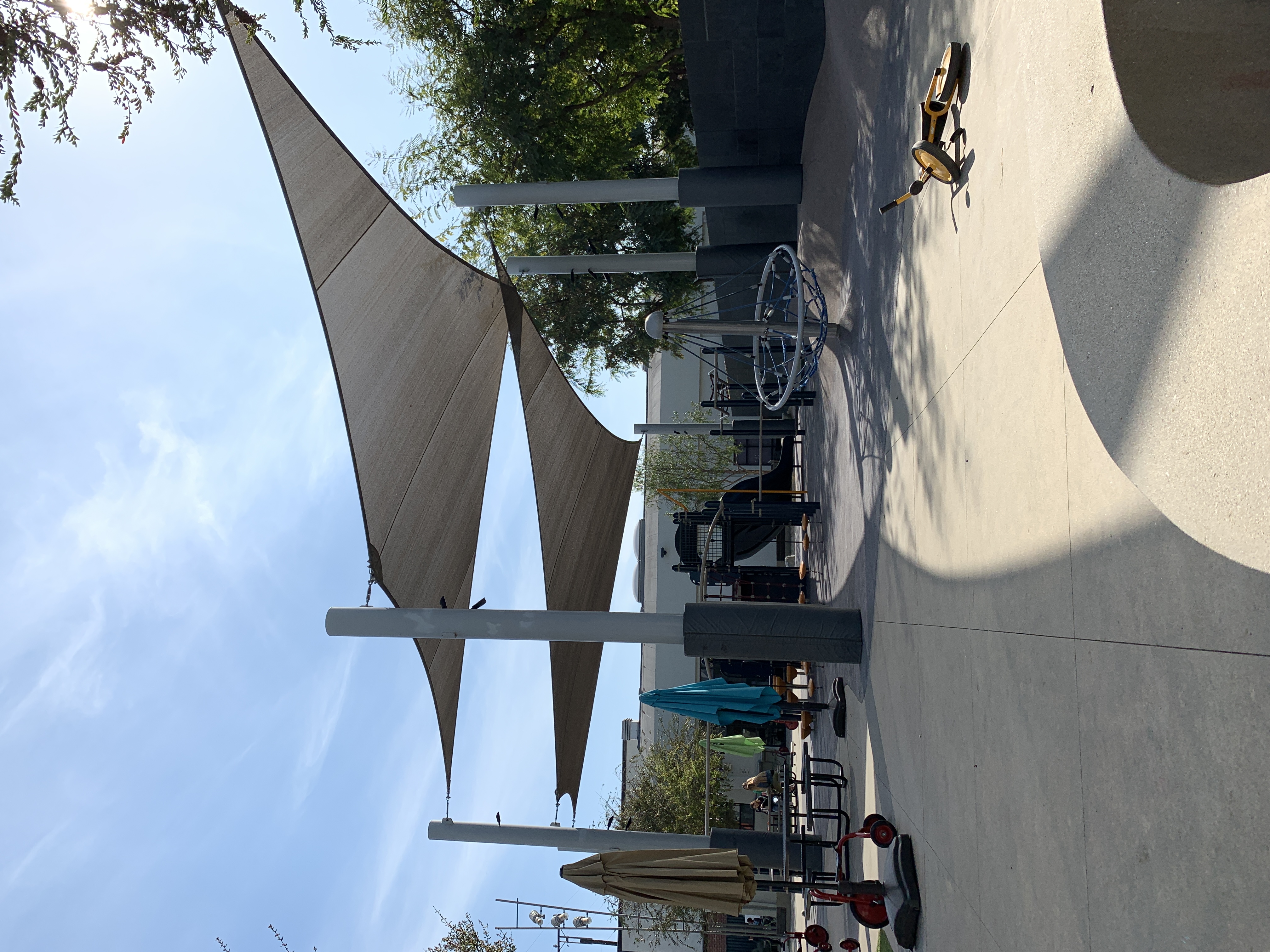 Large fabric shade structure covering playground equipment at a public park