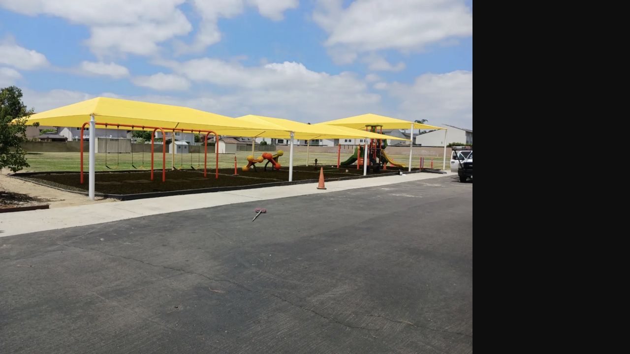 Yellow hip-roof canopy installed over an outdoor school activity area