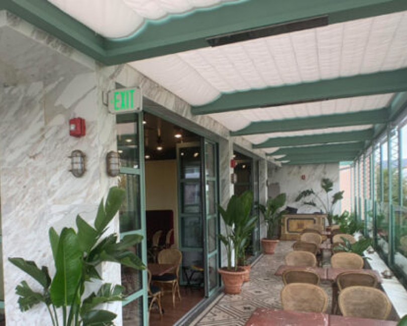 Green-and-white slide-on-wire canopy over restaurant seating, San Diego County
